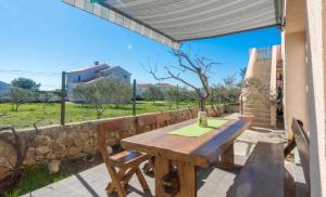 un tavolo in legno con sedie e un muro in pietra di Apartment Tomislav a Vir (Puntadura)