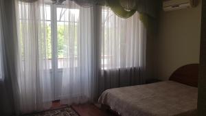 a bedroom with white curtains and a bed and a window at Золотой Берег in Poltava