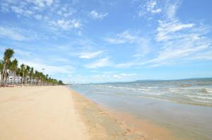 uma praia com uma fileira de palmeiras e o oceano em Scandia Beach Hotel em Praia de Jomtien