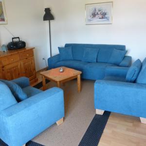 a living room with blue couches and a table at Pension Ridder in Marienmünster