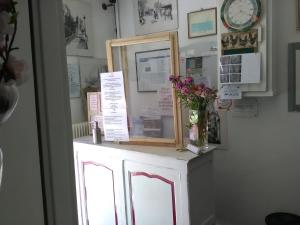 een spiegel bovenop een kast met bloemen erop bij Le Parisien in Saintes