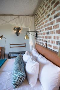 a bedroom with a bed with pillows and a brick wall at Gondwana Etosha Safari Lodge in Okaukuejo
