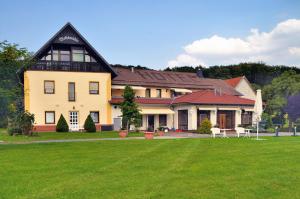 una casa grande con un césped verde delante de ella en Ferienhotel Wolfsmühle, en Rodishain