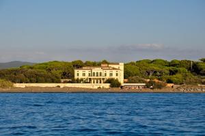 una gran casa blanca en una playa junto al agua en Luxury apartment inside beachfront villa, en Donoratico