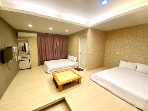 a hotel room with two beds and a table at Fengjia Jocy House in Taichung