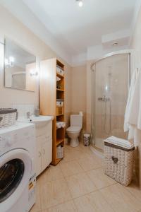 a bathroom with a toilet and a sink and a washing machine at Apartament Molo in Giżycko