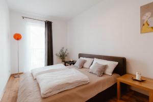 a bedroom with a bed with white sheets and a window at Apartament Molo in Giżycko