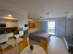 a hotel room with a bed and tables and a kitchen at Muro Alto Marulhos in Porto De Galinhas