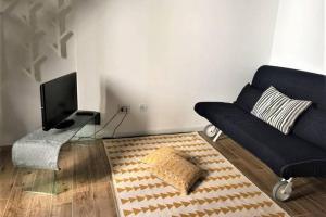 uma sala de estar com um sofá preto e uma televisão em Dock78 - MiniLoft in Catania Center em Catânia