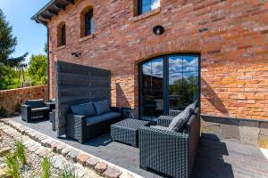 un patio con muebles de mimbre y un edificio de ladrillo en DOMKI APARTAMENTOWE CHMIELÓWKA, en Chmielno