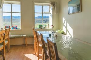 a dining room with a table and chairs and windows at Hvammur 2 Guesthouse in Blönduós