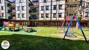a playground in front of a large building at Rowy Apartamenty Jantar in Rowy