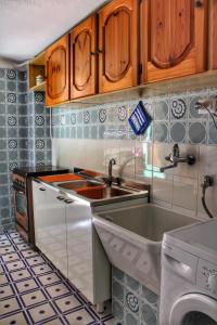 a kitchen with wooden cabinets and a sink and a dishwasher at Gerani House in Cefalù