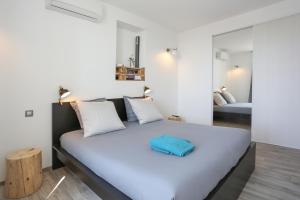 ein Schlafzimmer mit einem weißen Bett und einem blauen Kissen darauf in der Unterkunft SunSet Cassis in Cassis