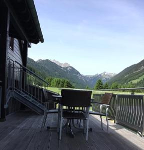 a table and two chairs on a deck with mountains at Ferienwohnung Birkentalblick in Nesselwängle
