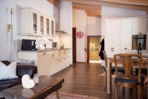 a kitchen with white cabinets and a table in a room at Ferienwohnung Birkentalblick in Nesselwängle