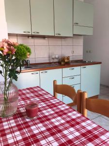 a kitchen with a table with a vase of flowers on it at Apartmani Tomelić in Orebić