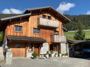 a large wooden house with a car parked in front at Chalet 4M Les Carroz et son Spa in Les Carroz d'Araches