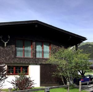 ein Haus mit roten und weißen Fenstern darauf in der Unterkunft Ferienwohnung Birkentalblick in Nesselwängle