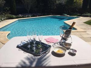 ナルボンヌにあるVilla privée indépendante et Luxueuse au calmeのプールサイドのテーブル(グラス付)とワイン1本