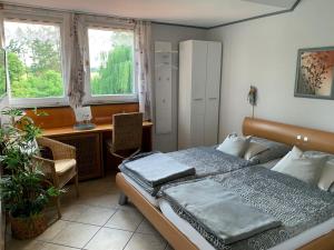 a bedroom with a bed and a desk and two windows at Gästehaus Villa Kreativ Susanne Lay in Bad Münder am Deister