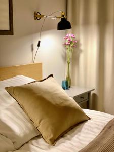 Una cama con una almohada y un jarrón de flores sobre una mesa en Apartamenty Park, en Mielno