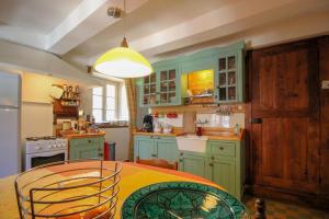 cocina con armarios verdes, mesa y luz en Gite Les genêts, baronnies provençales, en Montjay
