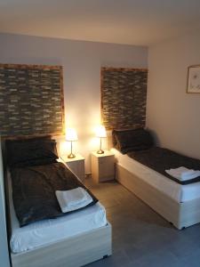 2 Betten in einem Zimmer mit 2 Lampen an Tischen in der Unterkunft Andromachi Apartments in Jembke