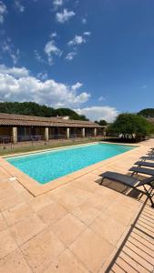 a swimming pool with chairs and a building at Appartements " Le Clos De La Cerisaie" in Castillon-du-Gard