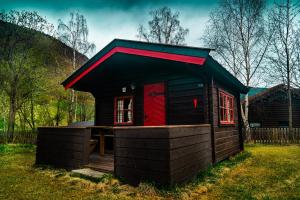 a small house with a red door in the grass at Kirketeigen Camping in Kvam