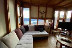 ein Wohnzimmer mit einer weißen Couch in einem Zimmer mit Fenstern in der Unterkunft Belle maison Vue imprenable lac de Serre-Ponçon in Prunières