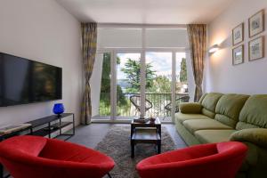 sala de estar con sofá verde y sillas rojas en Villa Lovor en Trogir