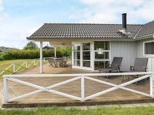 a deck with chairs and tables on a house at 8 person holiday home in Lemvig in Lemvig