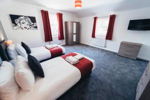 two beds in a room with red curtains at The Stay Company, Mill Street in Derby