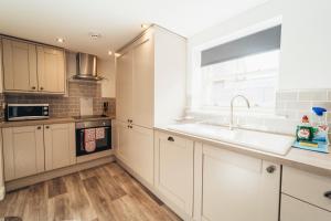 a kitchen with white cabinets and a sink and a window at The Stay Company, Mill Street in Derby