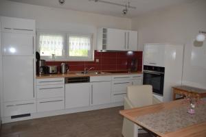 eine Küche mit weißen Schränken und einem Holztisch in der Unterkunft Ferienhaus Am Ramberg in Friedrichsbrunn