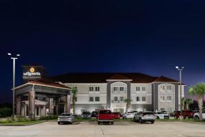 a hotel with cars parked in front of a parking lot at La Quinta by Wyndham Boutte in Boutte