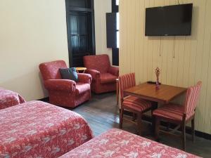 a hotel room with a table and chairs and a tv at Casa Elizabeth in Quetzaltenango