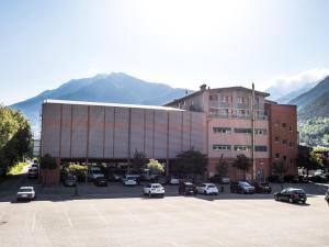 a large building with cars parked in a parking lot at Hotel Olympica in Brig