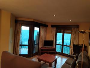 a living room with a couch and a tv and windows at Casa Simon 2 in Roda de Isábena