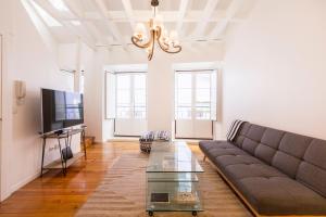 a living room with a couch and a tv at Stylish Getaway in a Mezzanine Flat by the Castle in Lisbon