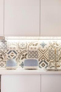 a kitchen with white cabinets and blue and white tiles at Stylish Getaway in a Mezzanine Flat by the Castle in Lisbon