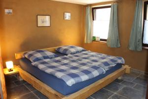 Un dormitorio con una cama con una manta de cuadros azul y blanco en Feriengut zum Trinkstorch, en Leinsweiler