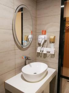 bagno con lavandino bianco e specchio di 7Days Premium Qingdao Ocean World Haiyou Road Subway Station Branch a Qingdao
