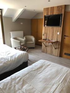 Habitación de hotel con cama, silla y TV en Hotel Val De La Cascade en Stavelot
