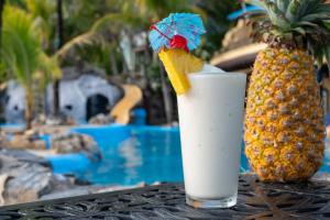 a drink sitting on a table next to a pineapple at Caribe Tesoro in West Bay