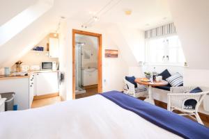 a bedroom with a bed and a table and a kitchen at The Bay Tree Studio in Thorpeness