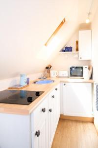 a kitchen with white cabinets and a sink at The Bay Tree Studio in Thorpeness