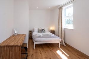 een slaapkamer met een bed, een bureau en een raam bij Three Tuns Apartments - Hazel in Pettistree