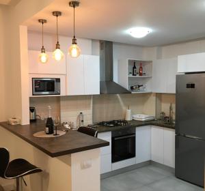 La cuisine est équipée de placards blancs et d'un réfrigérateur noir. dans l'établissement Adams Apartment Onix Blue, à Mamaia Nord – Năvodari